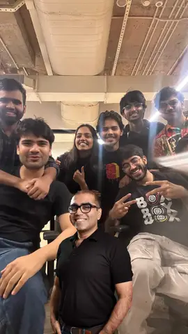 Everyone piled around a desk, looking up at the camera