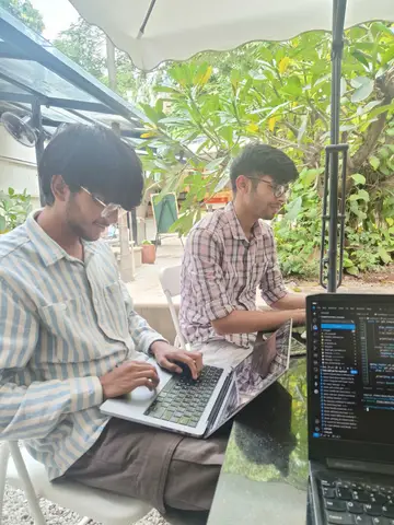 Two engineers working outdoors under a garden umbrella