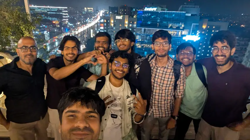 A rooftop group photo with the city lit up behind